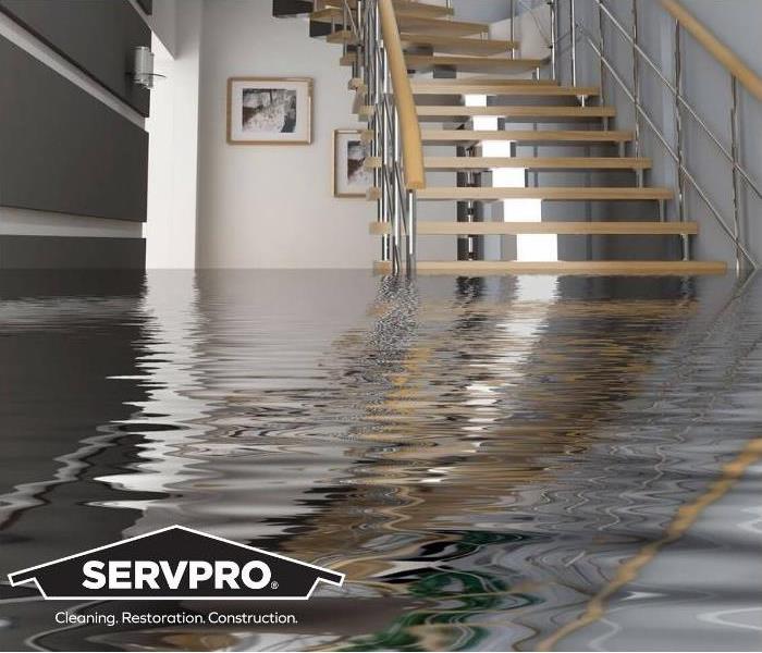 Flooded room with staircase and SERVPRO logo