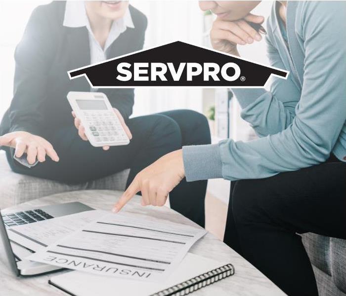 people discussing insurance policies and emergency forms with Servpro logo 