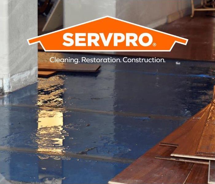 Water hidden under pulled up floorboards with SERVPRO logo 